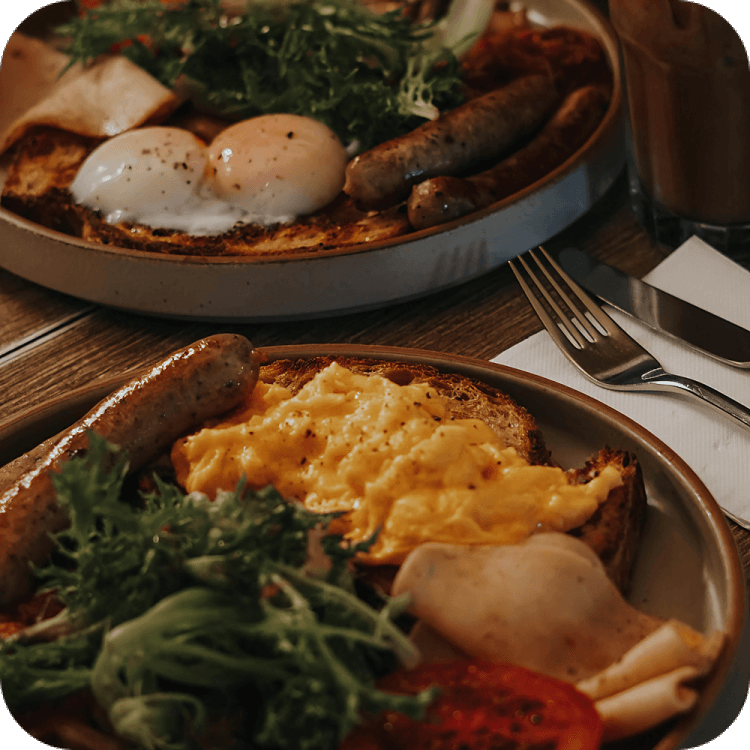 Two plates of food on a table with silverware.